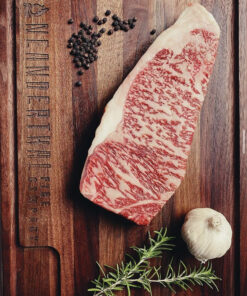 A raw Wagyu New York Steak on a cutting board.