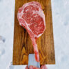 A raw tomahawk Wagyu Steak on a cutting board.