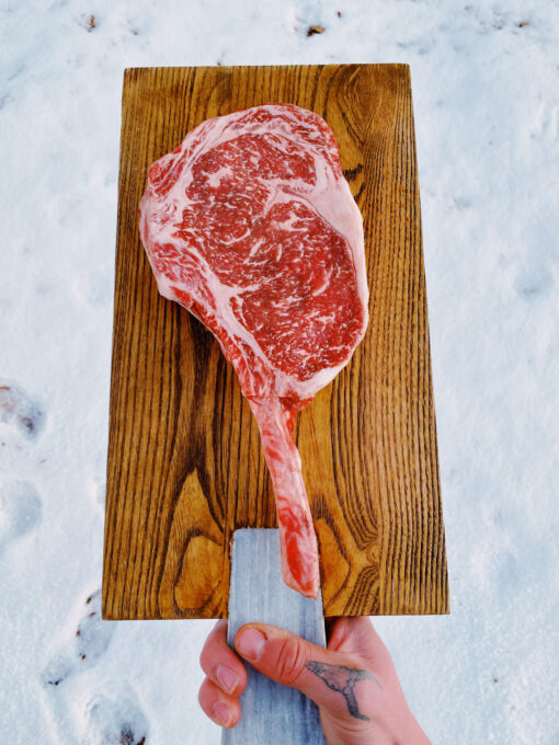 A raw tomahawk Wagyu Steak on a cutting board.